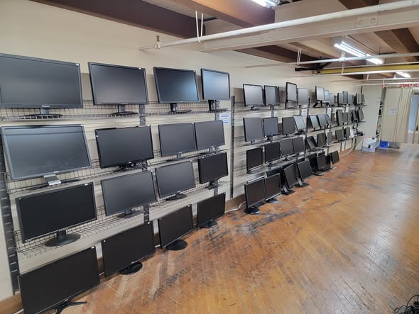 Rows of computer monitors on shelves along the shop wall